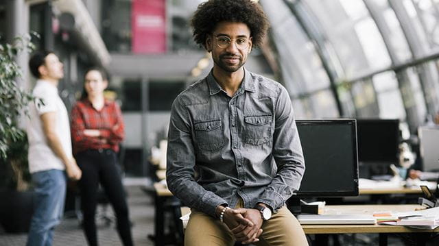 Happiness at work; man sat on desk